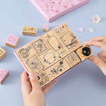 Tsuki ‘Sakura Journey’ Bullet Journal Stamp Set held in hands with cherry blossom petals on light blue background